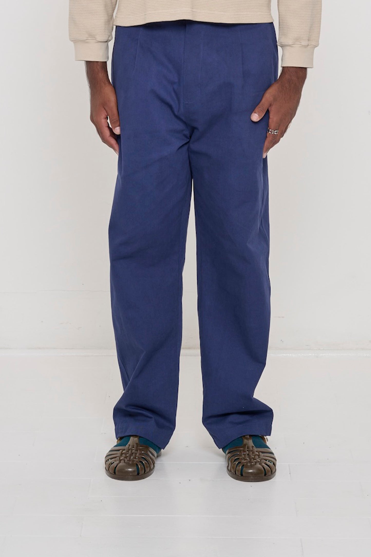Bottom half of a man wearing Cotton Twill Life Uniform Pants in Washed Navy,  showing the relaxed slim silhouette, front pleats.