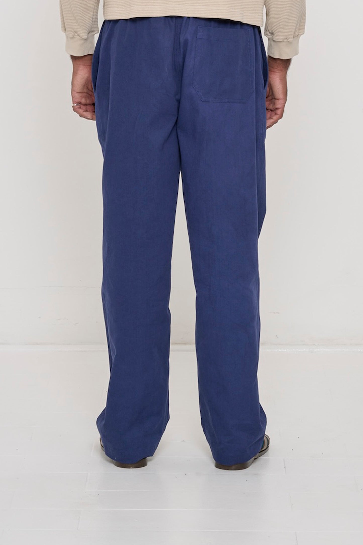 Back view: a man in Washed Navy Cotton Twill Life Uniform Pants, revealing a back pocket. Sized up for a relaxed fit.