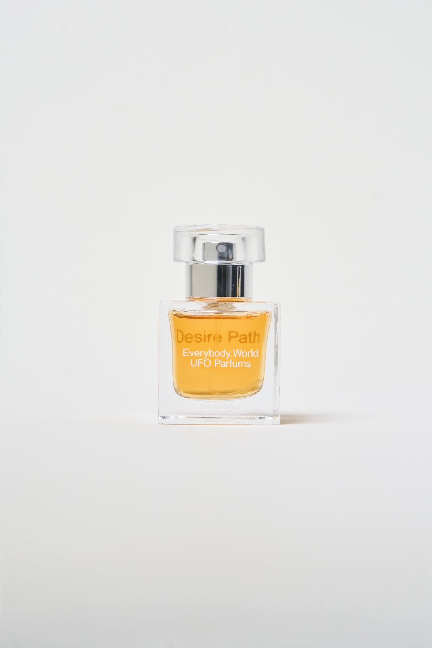 A clear glass bottle of Desire Path with a silver cap, containing a yellow-colored liquid.