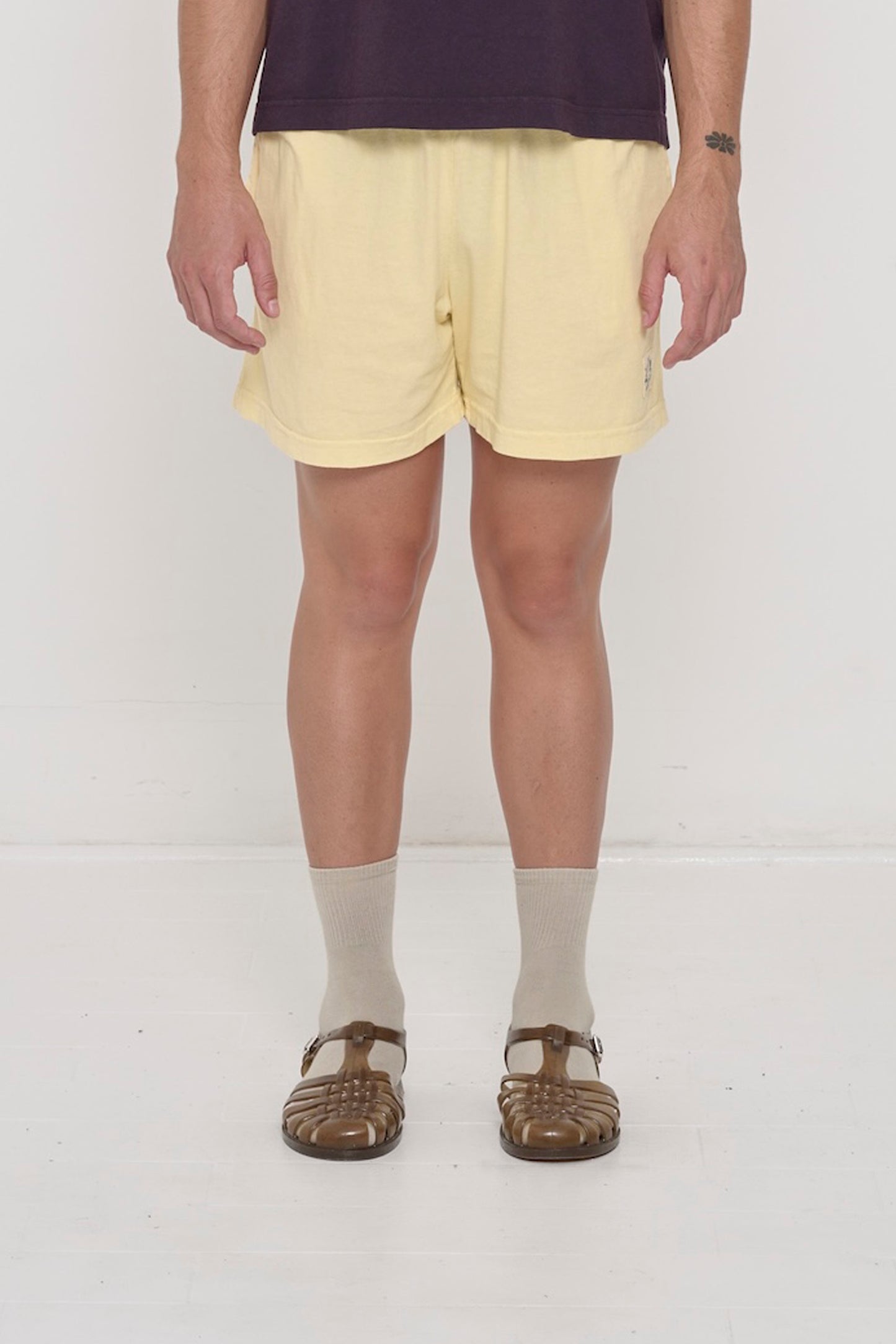 Waist down of a 6' person in Size L French Butter Everyday Shorts. Logo printed on bottom left. Hem at mid thigh.