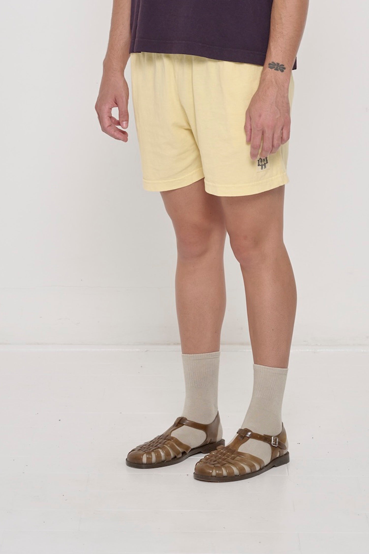 French Butter Everyday Shorts on a person, waist down, 45-degree front angle. Shows grey E.W logo on bottom left of shorts leg.