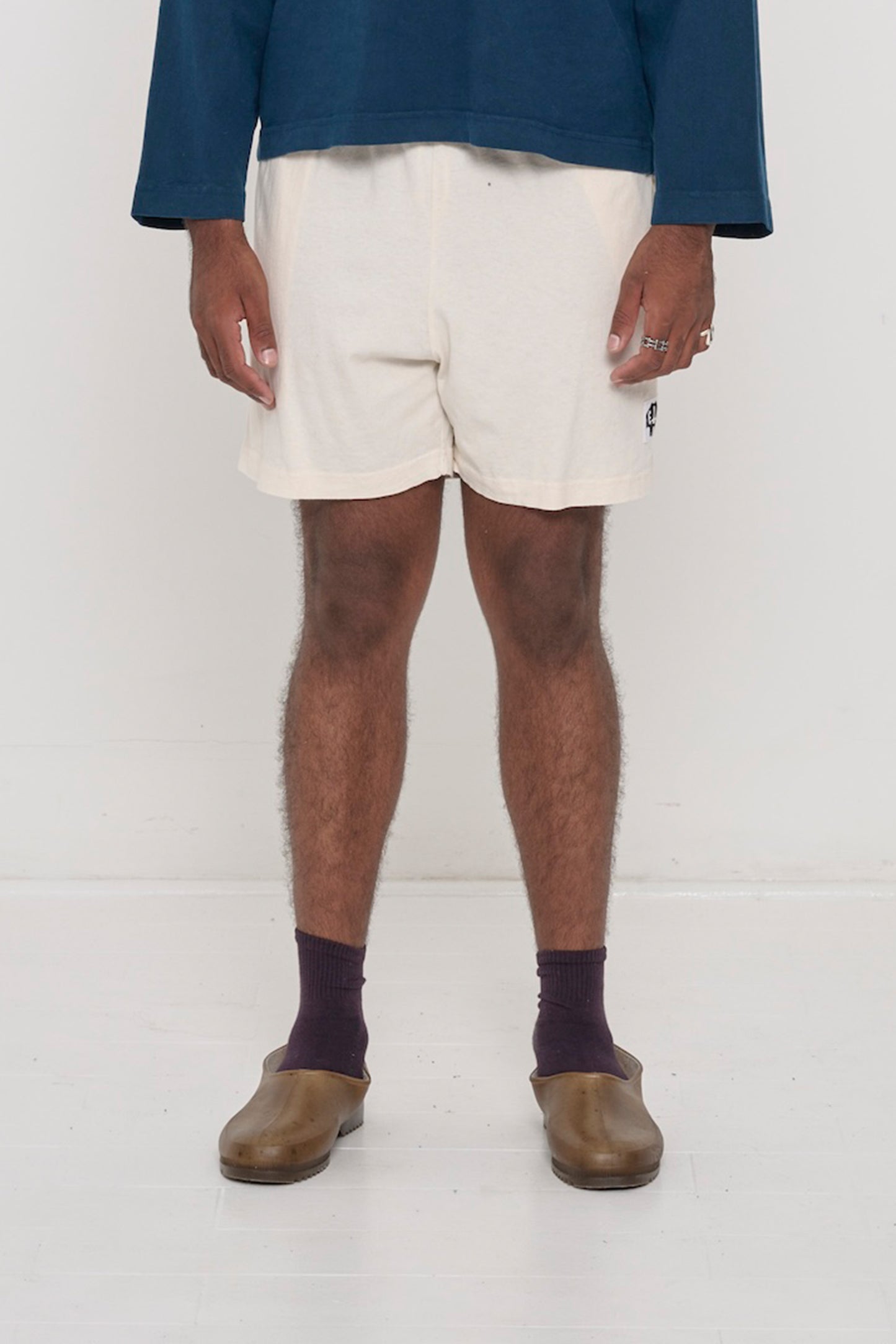 Waist down of a 6'2" person in Size L Scour Everyday Shorts. Logo printed on bottom left. Hem at mid thigh.