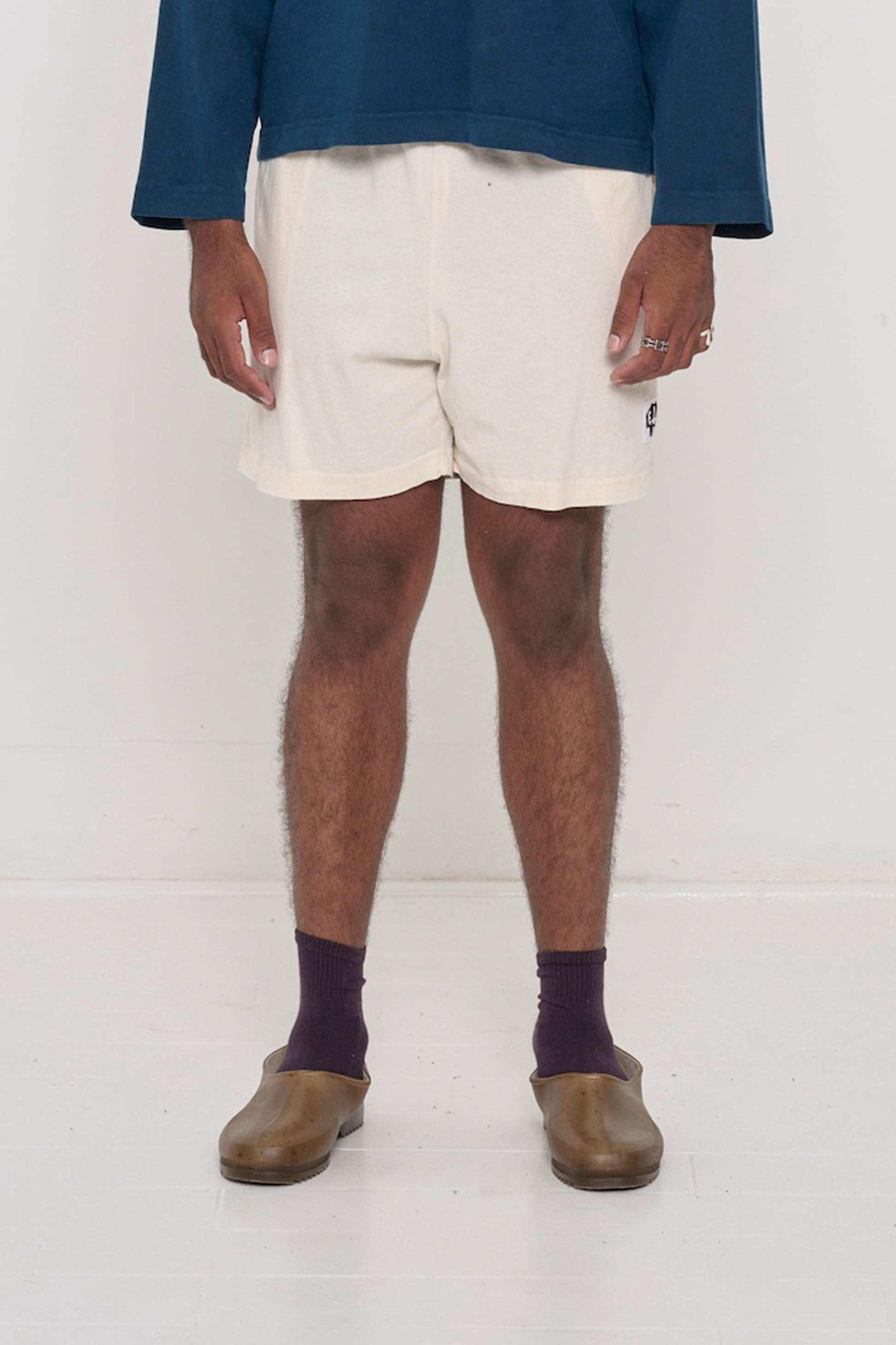 Waist down of a 6'2" person in Size L Scour Everyday Shorts. Logo printed on bottom left. Hem at mid thigh.