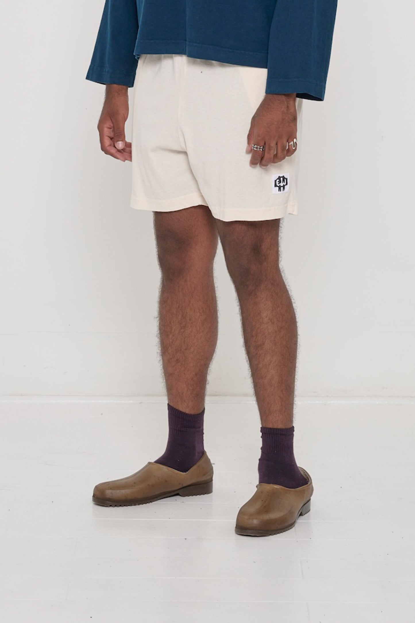Scour Everyday Shorts on a person, waist down, 45-degree front angle. Shows white E.W logo on bottom left of shorts leg.