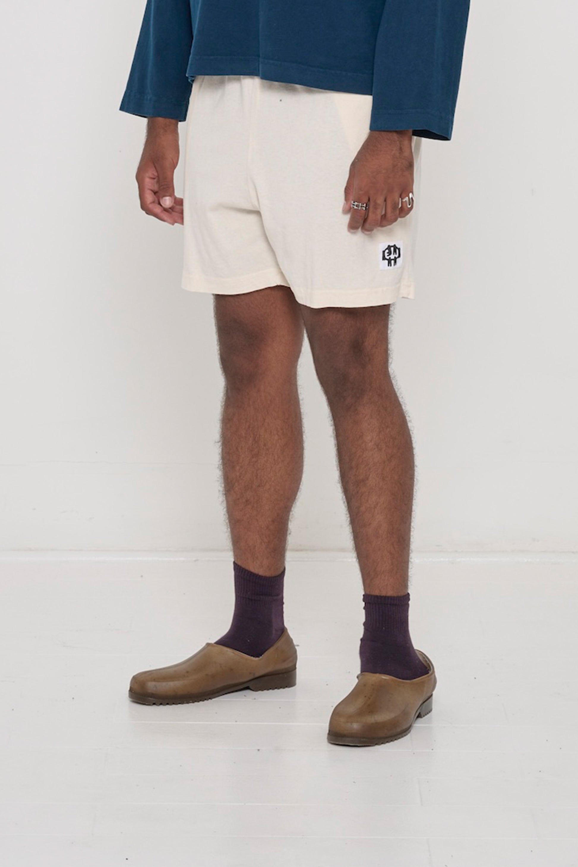 Scour Everyday Shorts on a person, waist down, 45-degree front angle. Shows white E.W logo on bottom left of shorts leg.