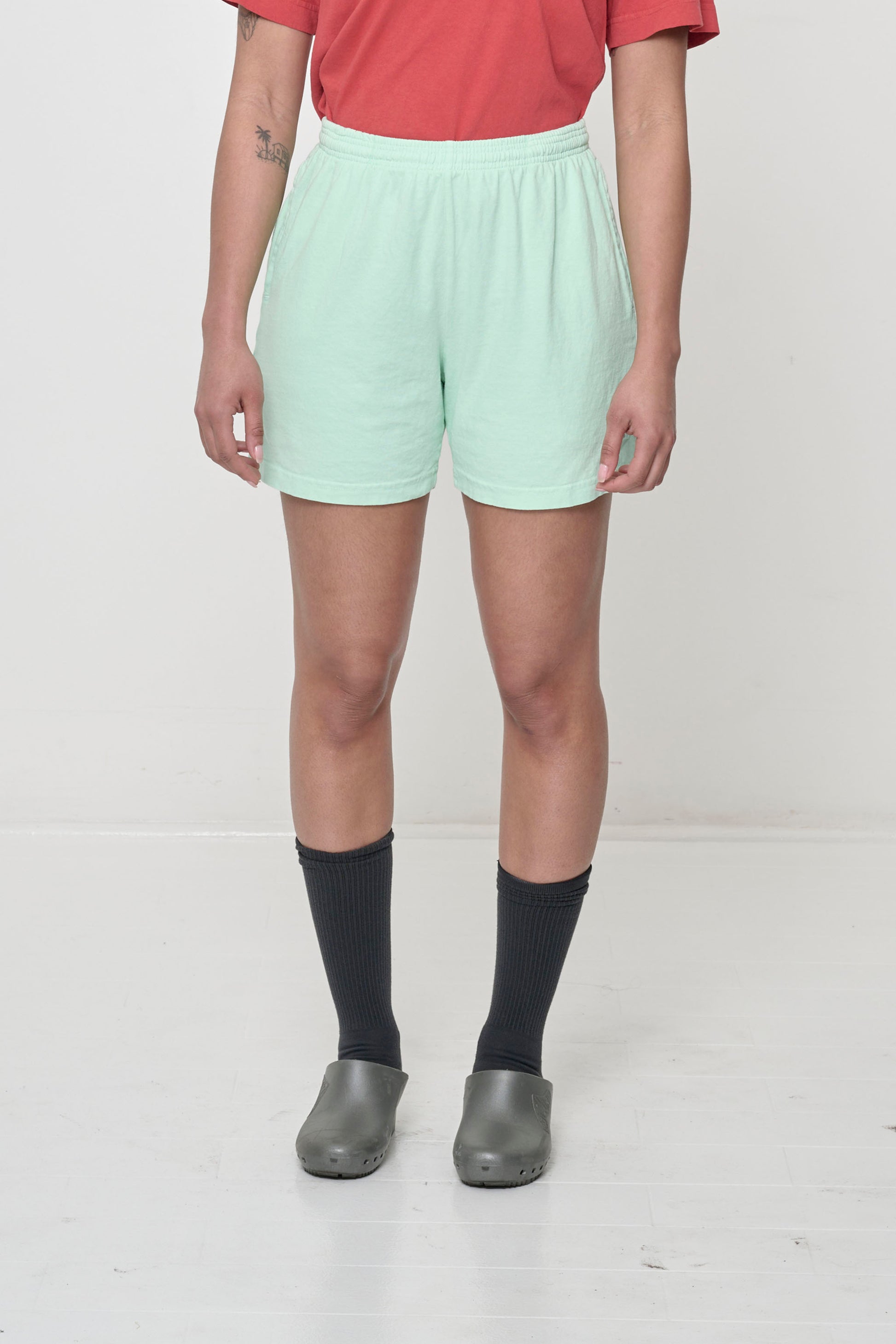 Light green Sea Glass Everyday Shorts on model, front. Relaxed fit, mid-thigh, elastic waist, side pockets.