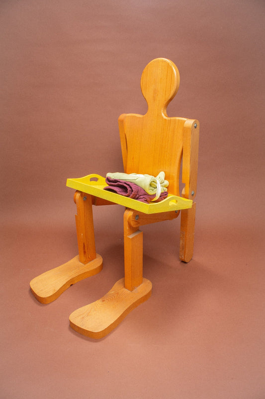 Wooden mannequin chair with Cardamom light green and Burgundy shorts folded on its lap.