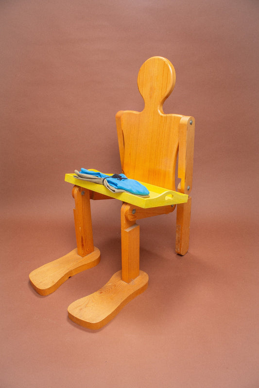 Wooden mannequin chair with Azul blue and Sage grey green tees folded on its lap.