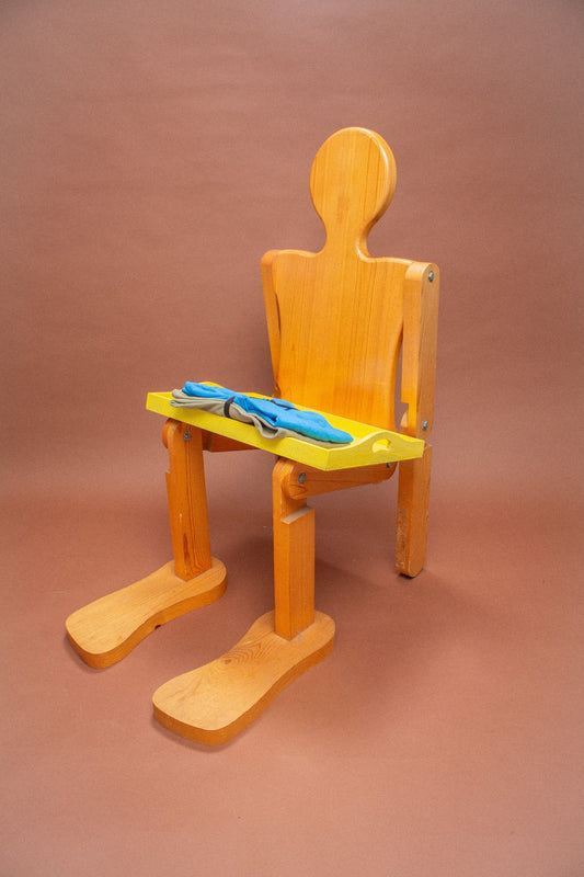 Wooden mannequin chair with Azul blue and Cardamom light green tees folded on its lap.
