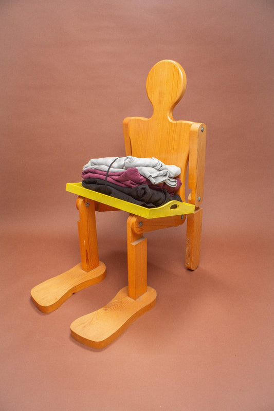 Wooden mannequin chair with Grey, Black and Burgundy sweatshirts folded on its lap.