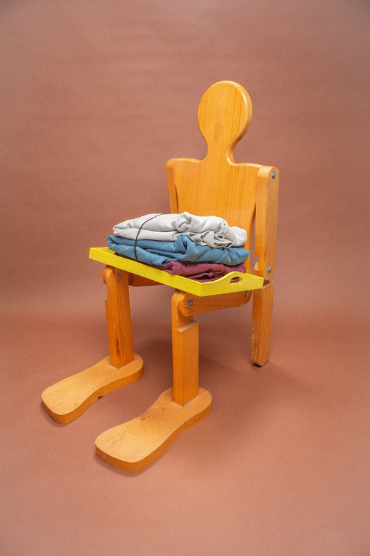 Wooden mannequin chair with Grey, Denim and Burgundy sweatshirts folded on its lap.