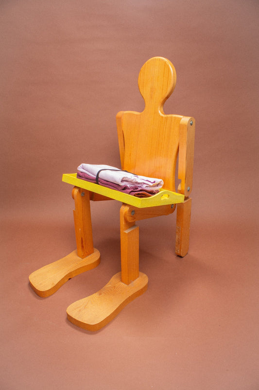 Wooden mannequin chair with Lavender and Burgundy sweatshirts folded on its lap.