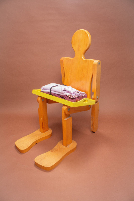 Wooden mannequin chair with Lavender and Burgundy sweatshirts folded on its lap.