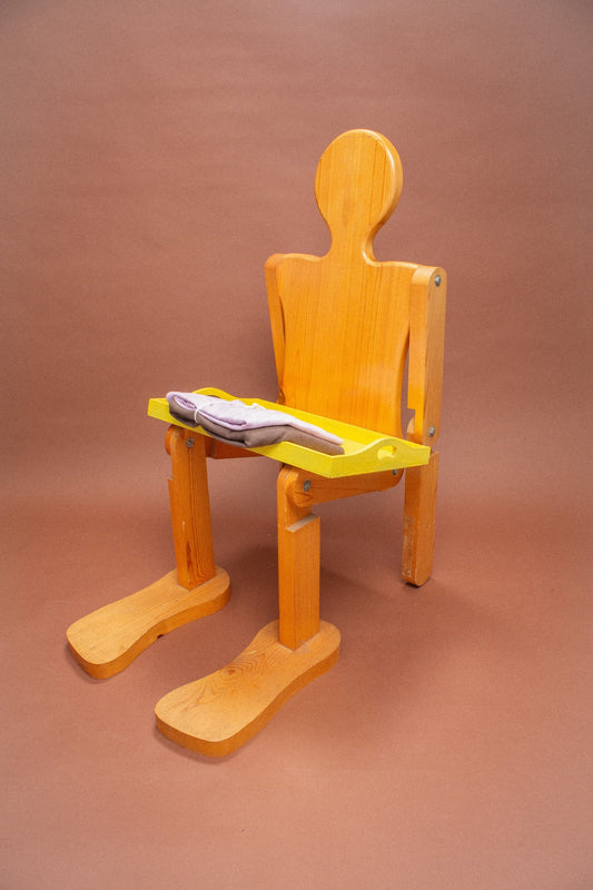 Wooden mannequin chair with Lavender and and Soil tees folded on its lap.