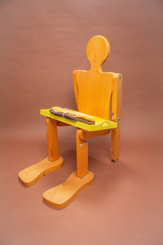Wooden mannequin chair with Amber and Soil tees folded on its lap.