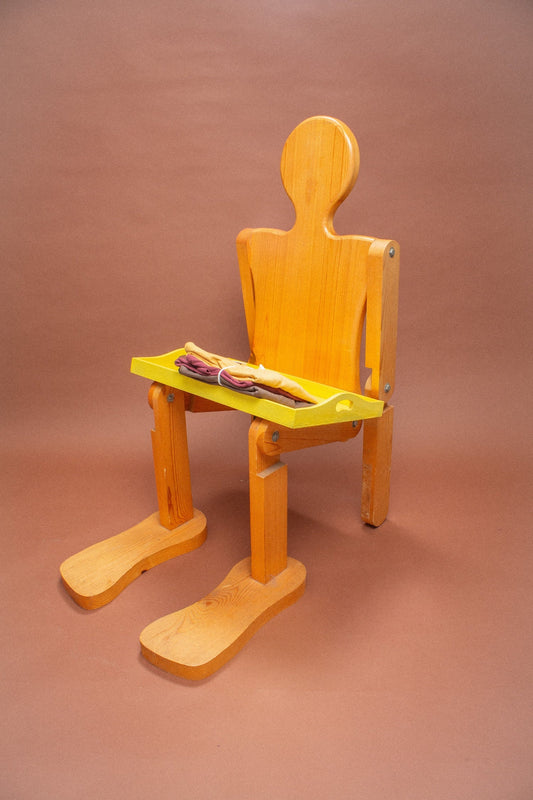 Wooden mannequin chair with Amber and Soil tees folded on its lap.