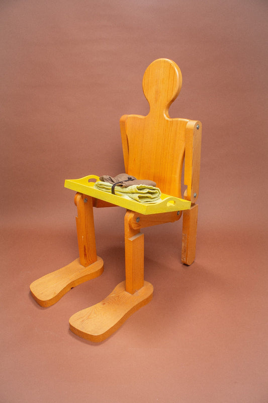 Wooden mannequin chair with Cardamom light green and brown folded shorts on its lap.