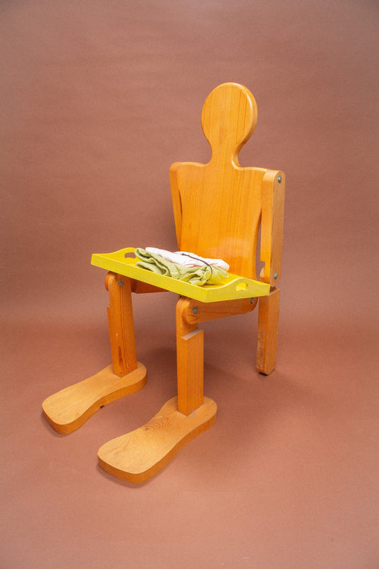 Wooden mannequin chair with Cardamom light green and Pink folded shorts on its lap.
