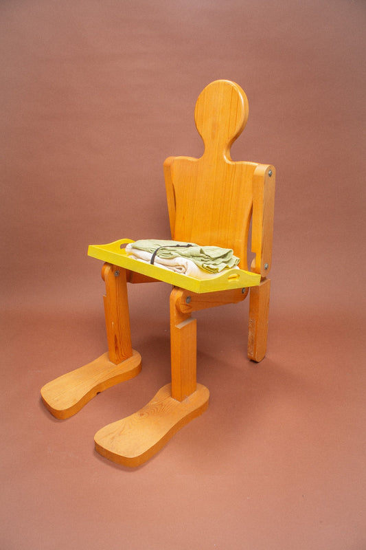 Wooden mannequin chair with Cardamom light green and Scour folded pants on its lap.