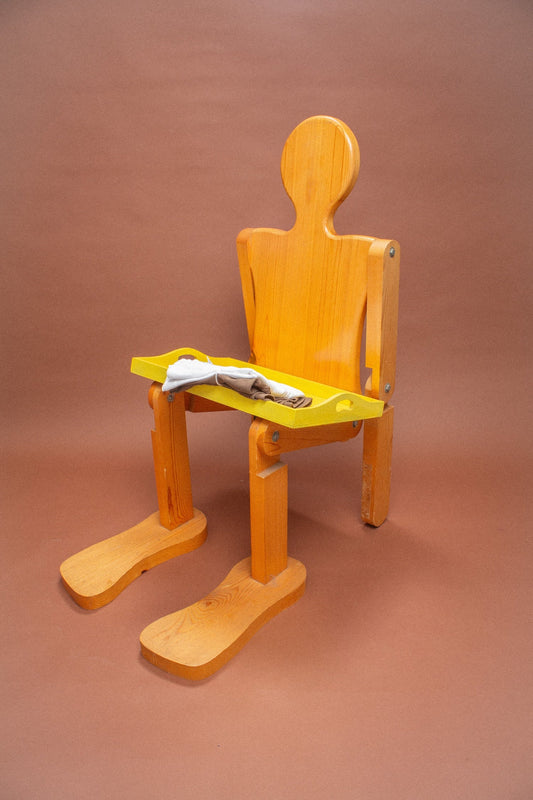 Wooden mannequin chair with brown and white folded tees on it.