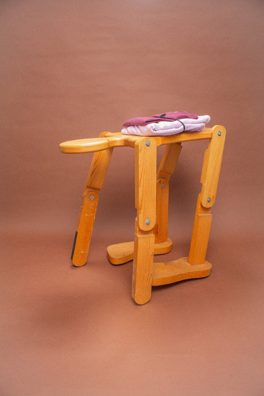 Wooden stool with a folded Burgundy tee and Lavender sweatshirt on it.