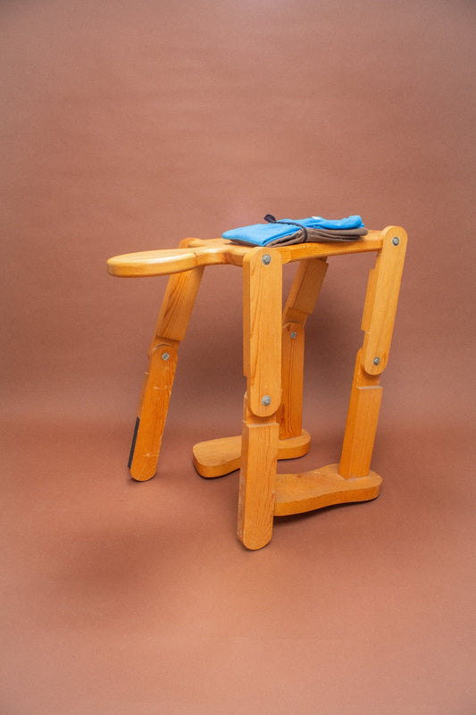 Wooden stool with blue and brown folded tees on it.