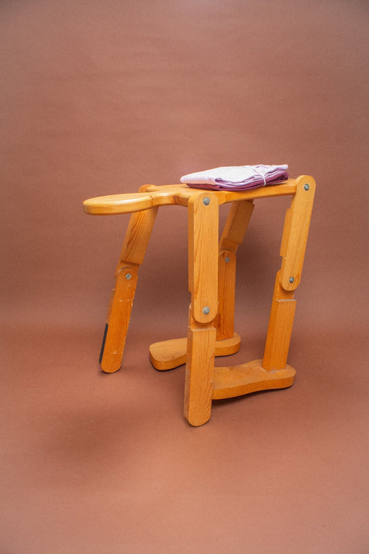 Wooden stool with folded lavender and burgundy tees on it.