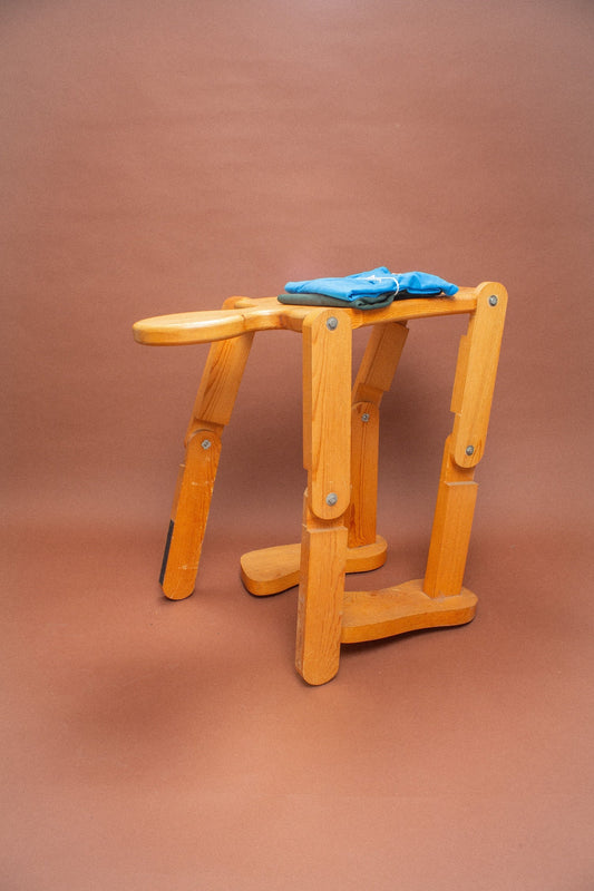 Wooden stool with blue and green folded tees on it.