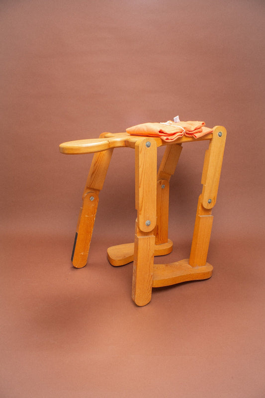 Wooden stool with two folded Peach tees on it.