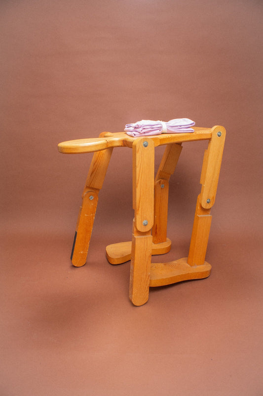 Wooden stool with 2 folded lavender tees on it.
