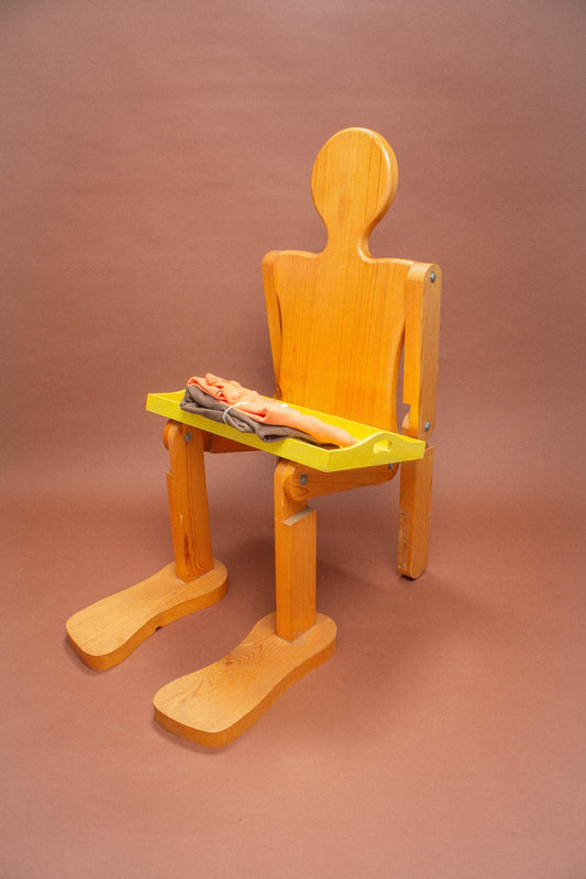 Wooden mannequin with folded peach and brown tees on a tray