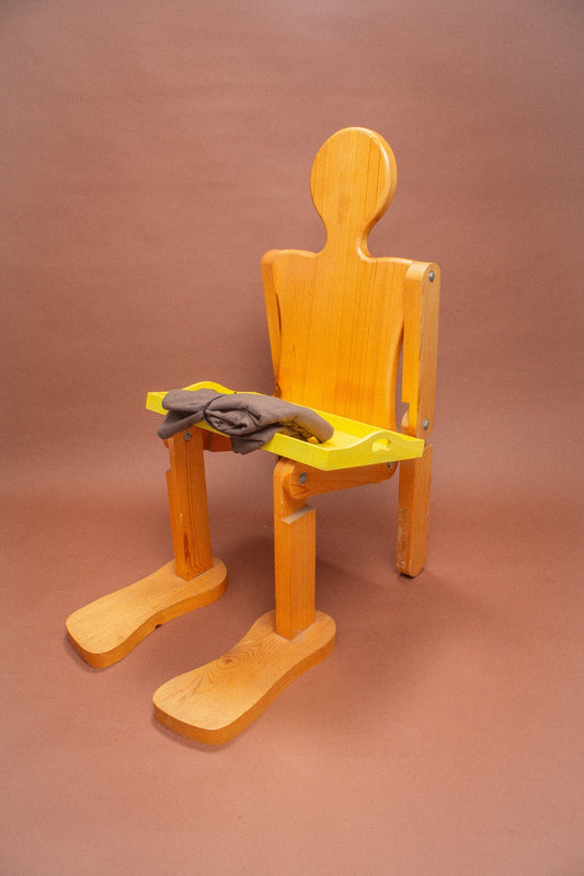 Wooden mannequin with a yellow tray holding brown garments