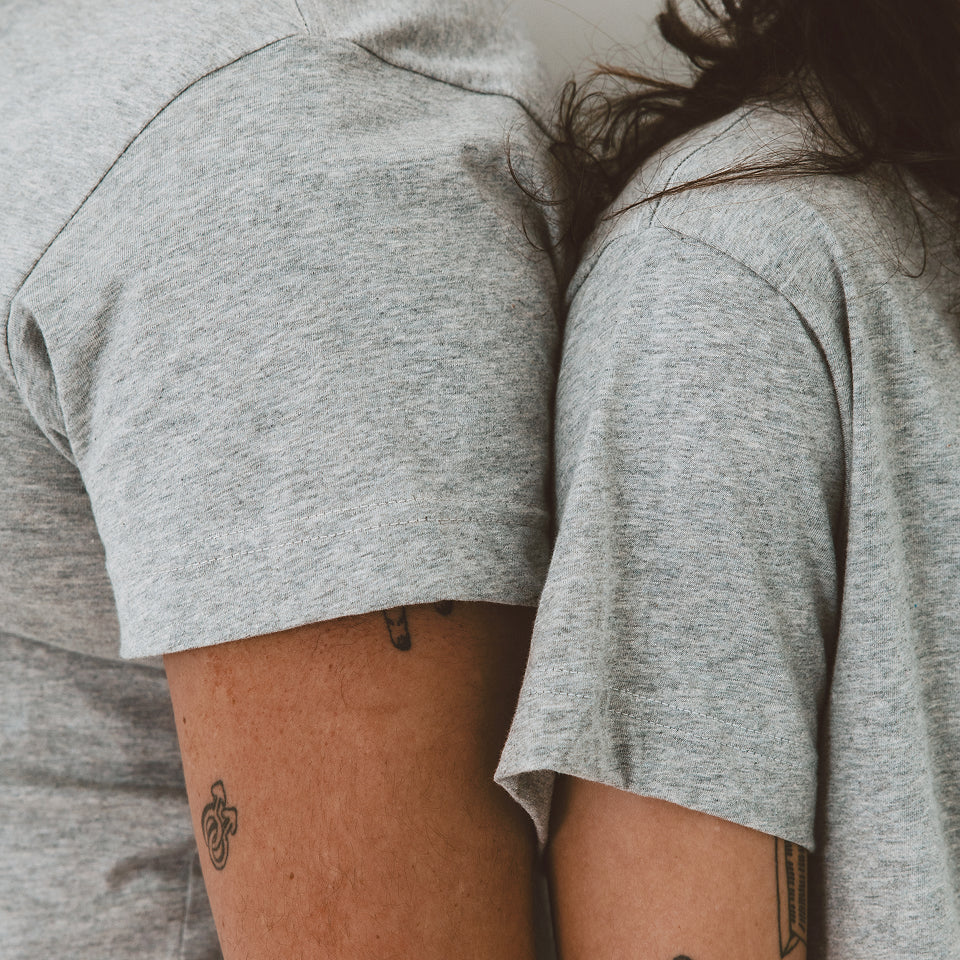 Close up of two people's shoulders standing back to back wearing Heather Boxier and Short Sleeve Tees.
