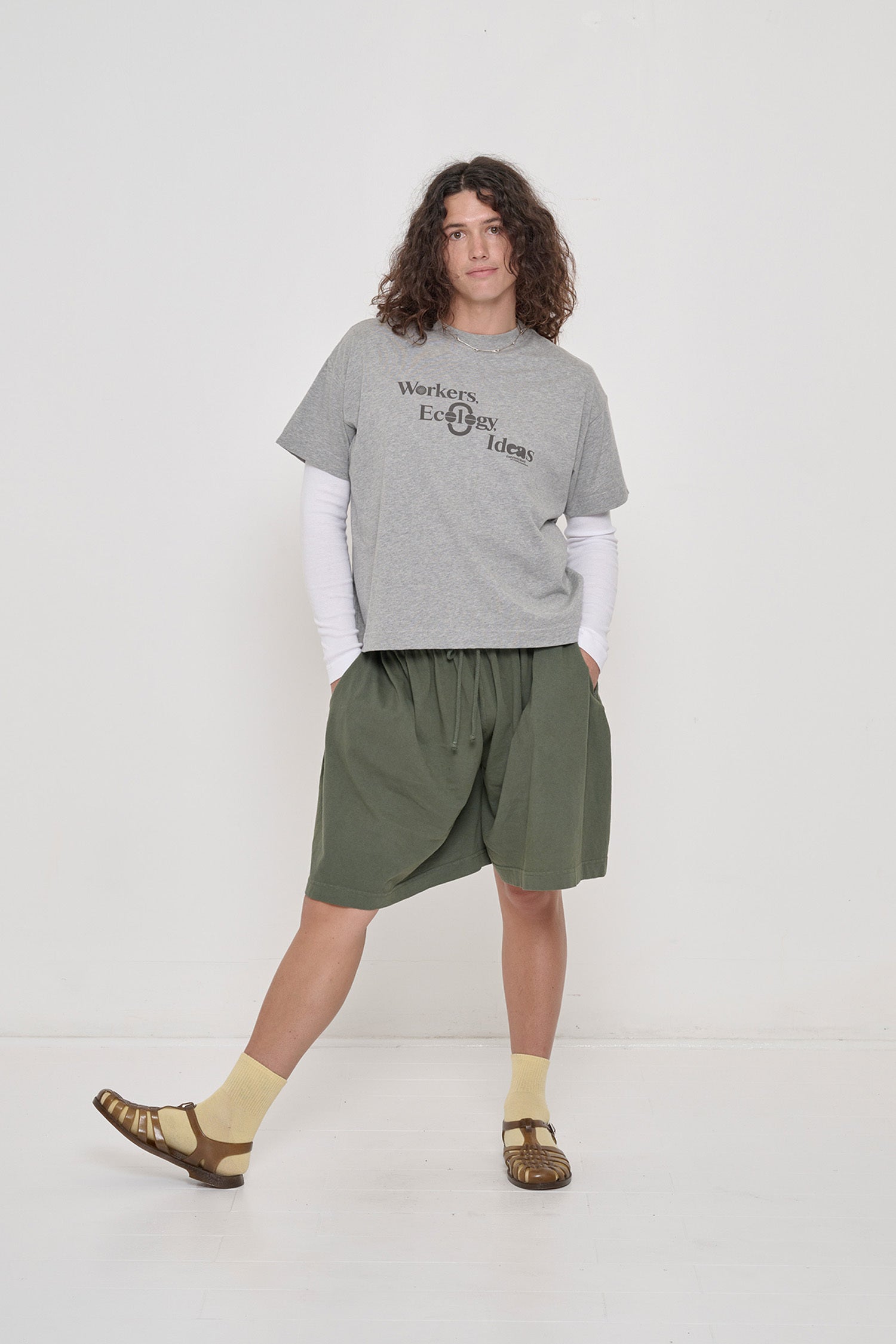 Person wearing Heather Boxier Tee that reads 'Workers, Ecology, Ideas' screenprinted on the front with Long Tubular Shorts.