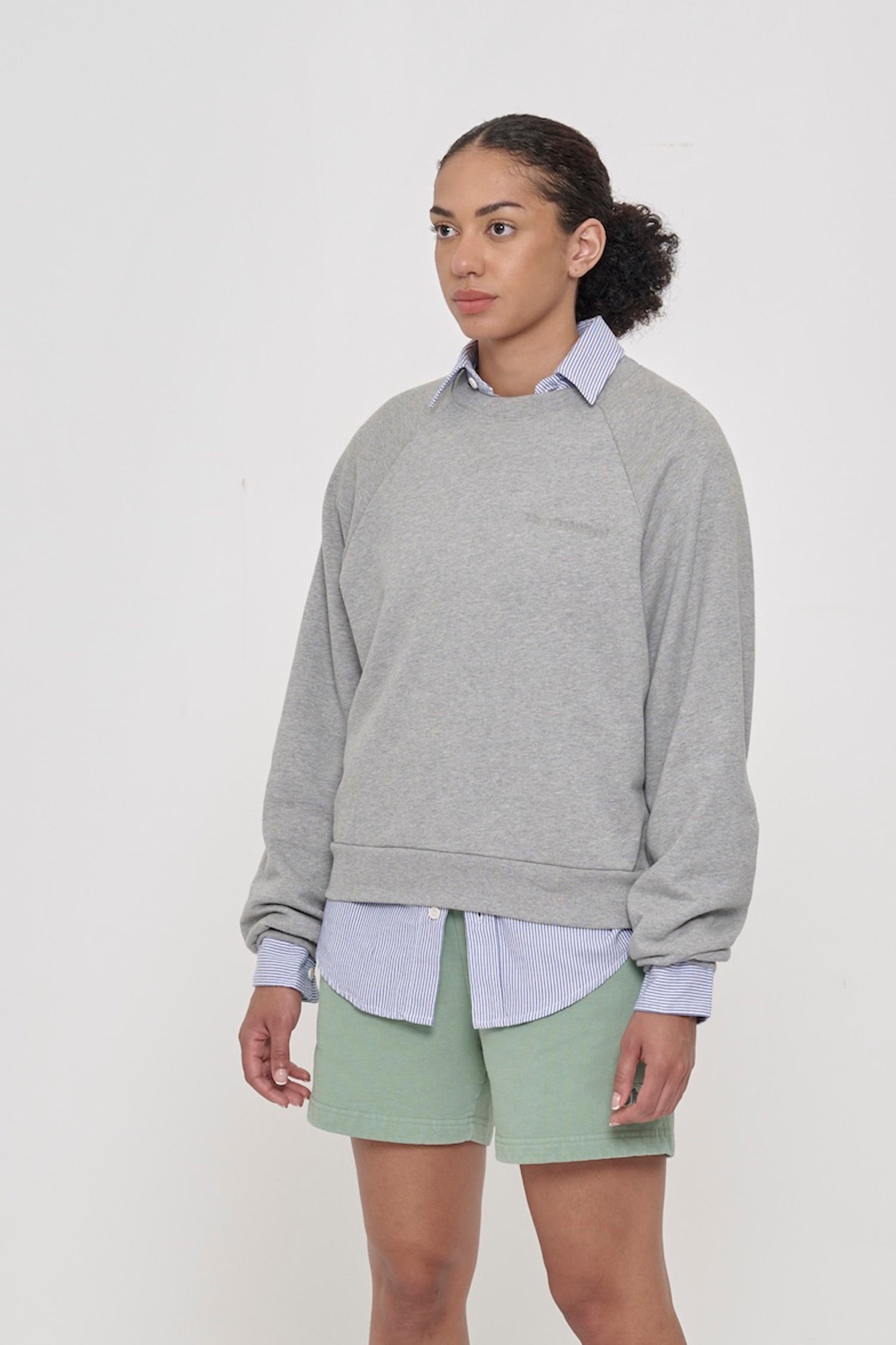 3/4 front view of woman wearing Heather Raglan Sweatshirt, showcasing sleeve's relaxed fit and raglan shoulder.