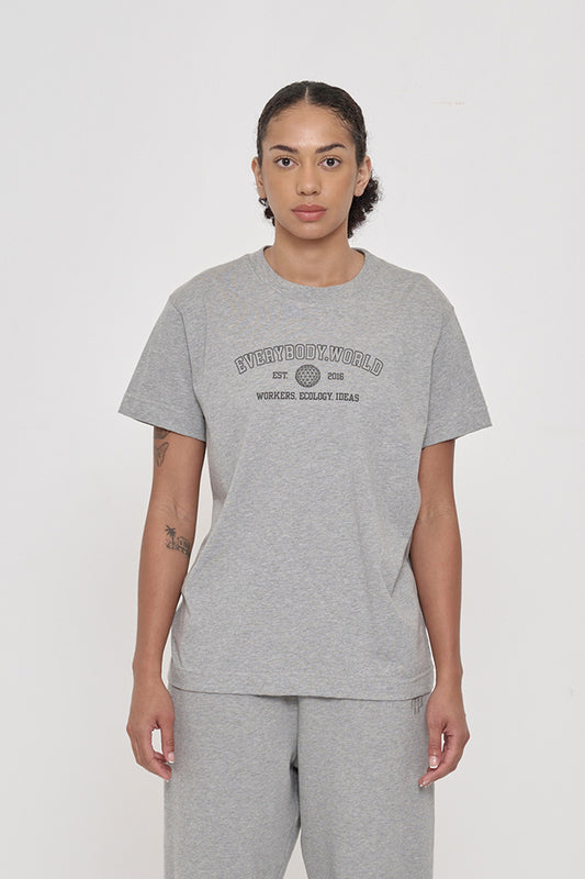 Woman in a Heather Short Sleeve Tee that reads 'Everybody.World' and 'Workers, Ecology, Ideas' screenprinted on the front.