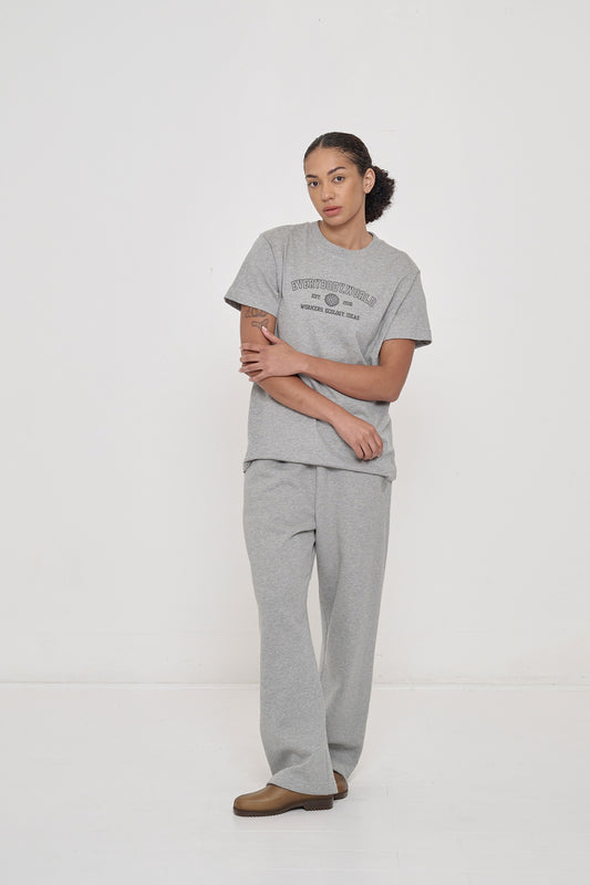 Woman in Heather Short Sleeve Tee with 'Everybody.World' and 'Workers, Ecology, Ideas' screenprinted across chest.