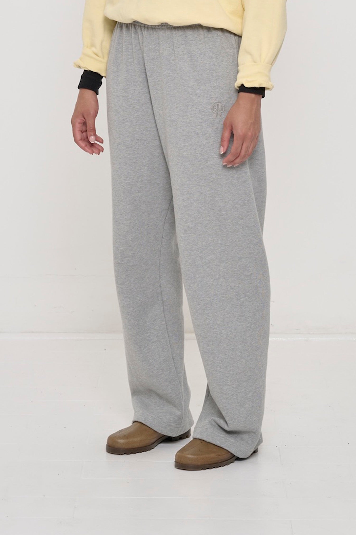Person turned 45 degrees, in Heather Sweatpants. Shows inseam and tonal logo embroidery near front side pocket.