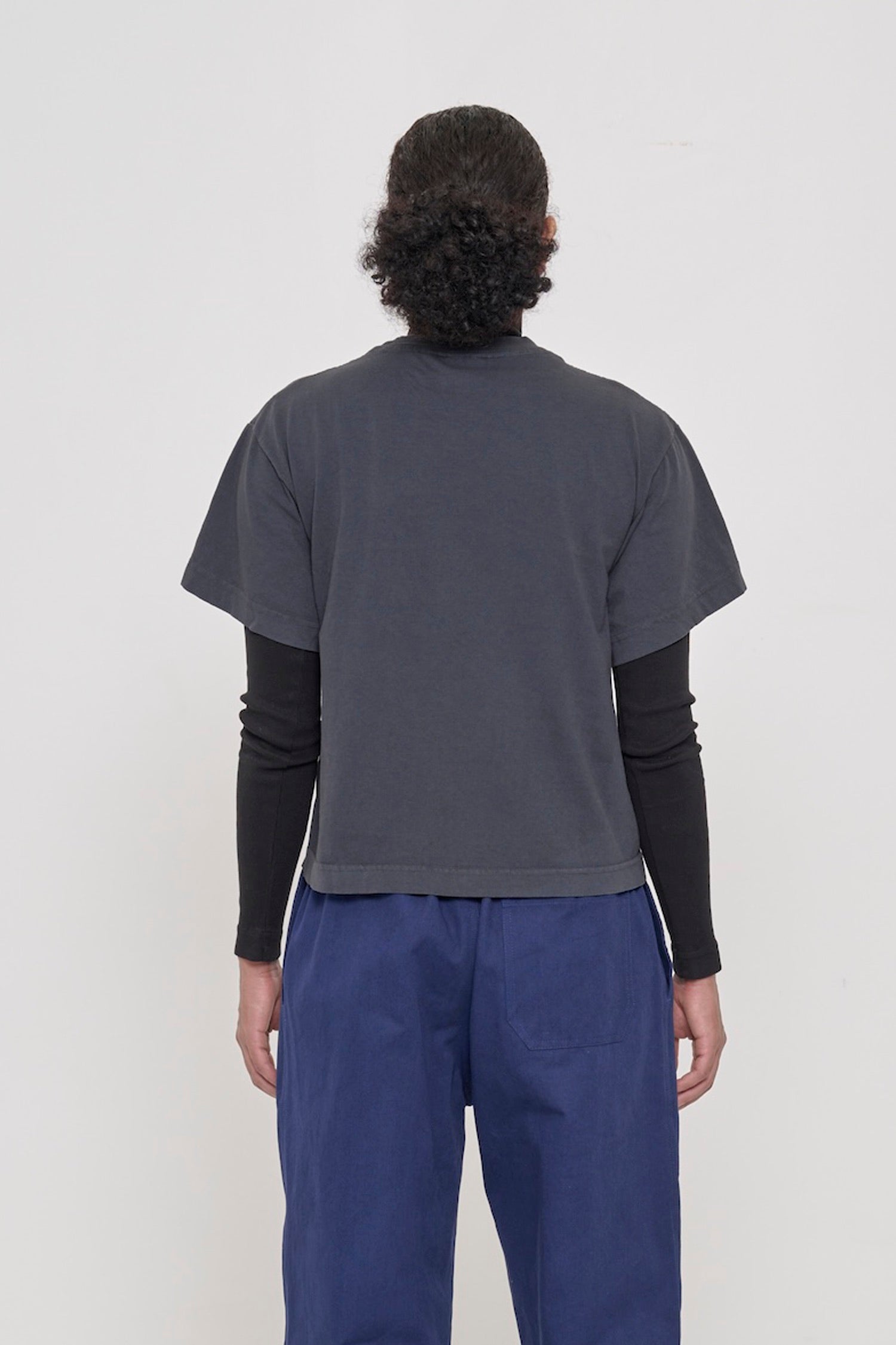 Back view of woman wearing Slate Heavyweight Boxier Trash Tee showing fabric drape and relaxed fit throughout.