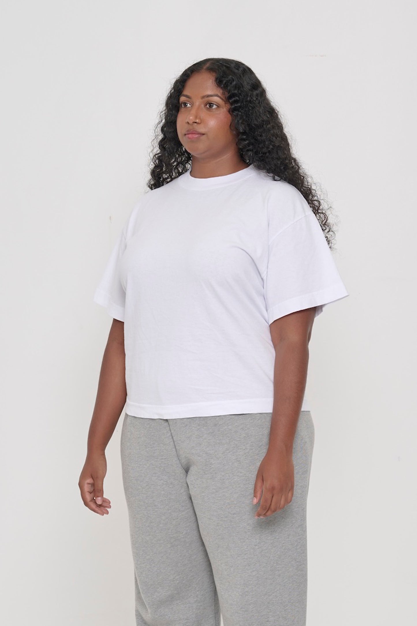 ¾ front view of a woman in a White Heavyweight Boxier Trash Tee: no side seams, wider than traditional short sleeves.