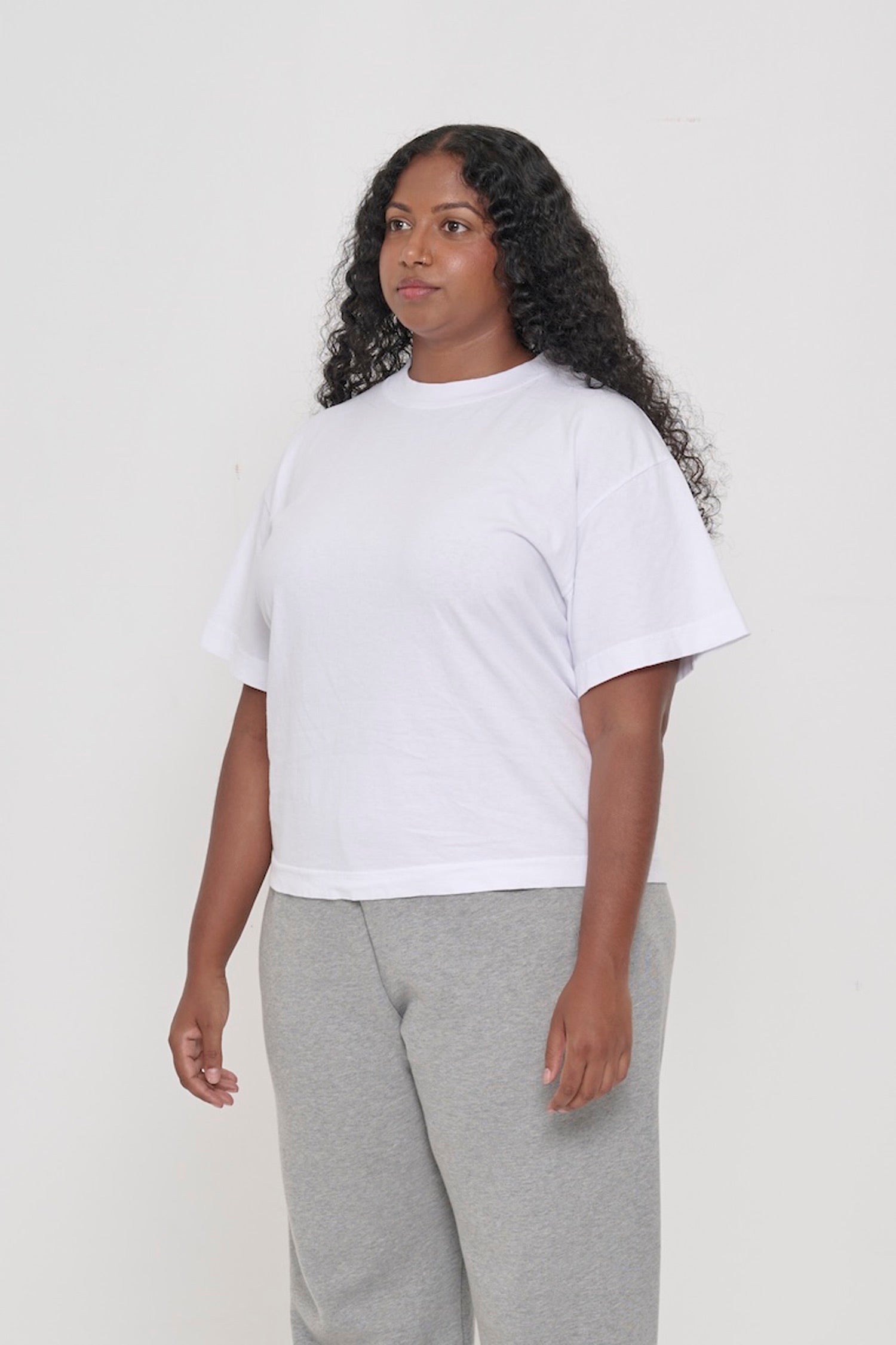 ¾ front view of a woman in a White Heavyweight Boxier Trash Tee: no side seams, wider than traditional short sleeves.