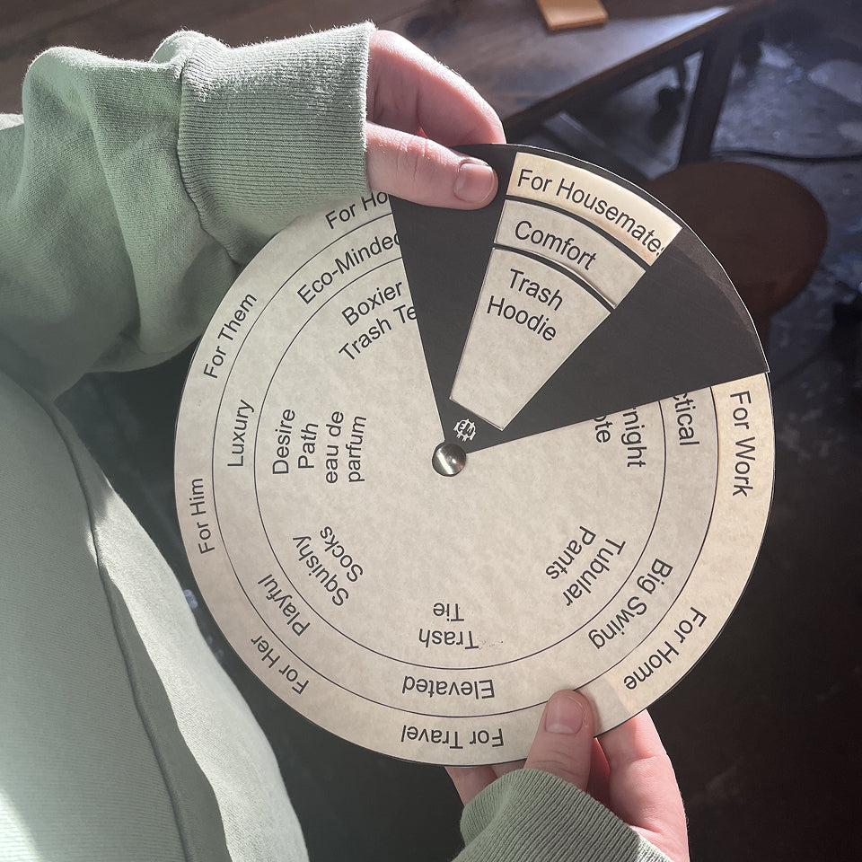 Person holding a circular selection tool with text on it, landing on "For Housemates, Comfort, Trash Hoodie" wearing a Trash Hoodie in Wasabi.