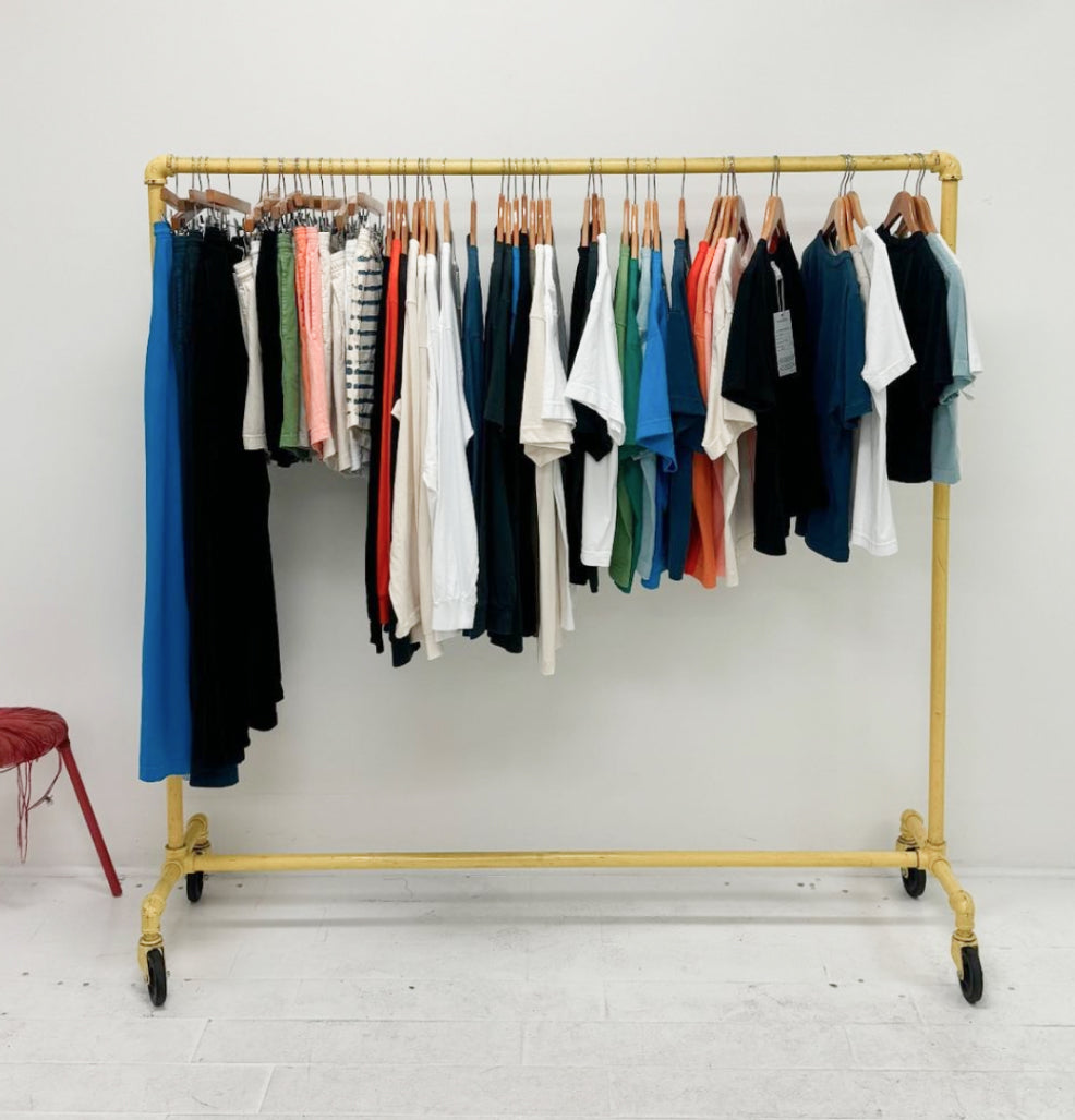 A bright yellow rolling racks hold clothing from the Everybody.World Trash Collection