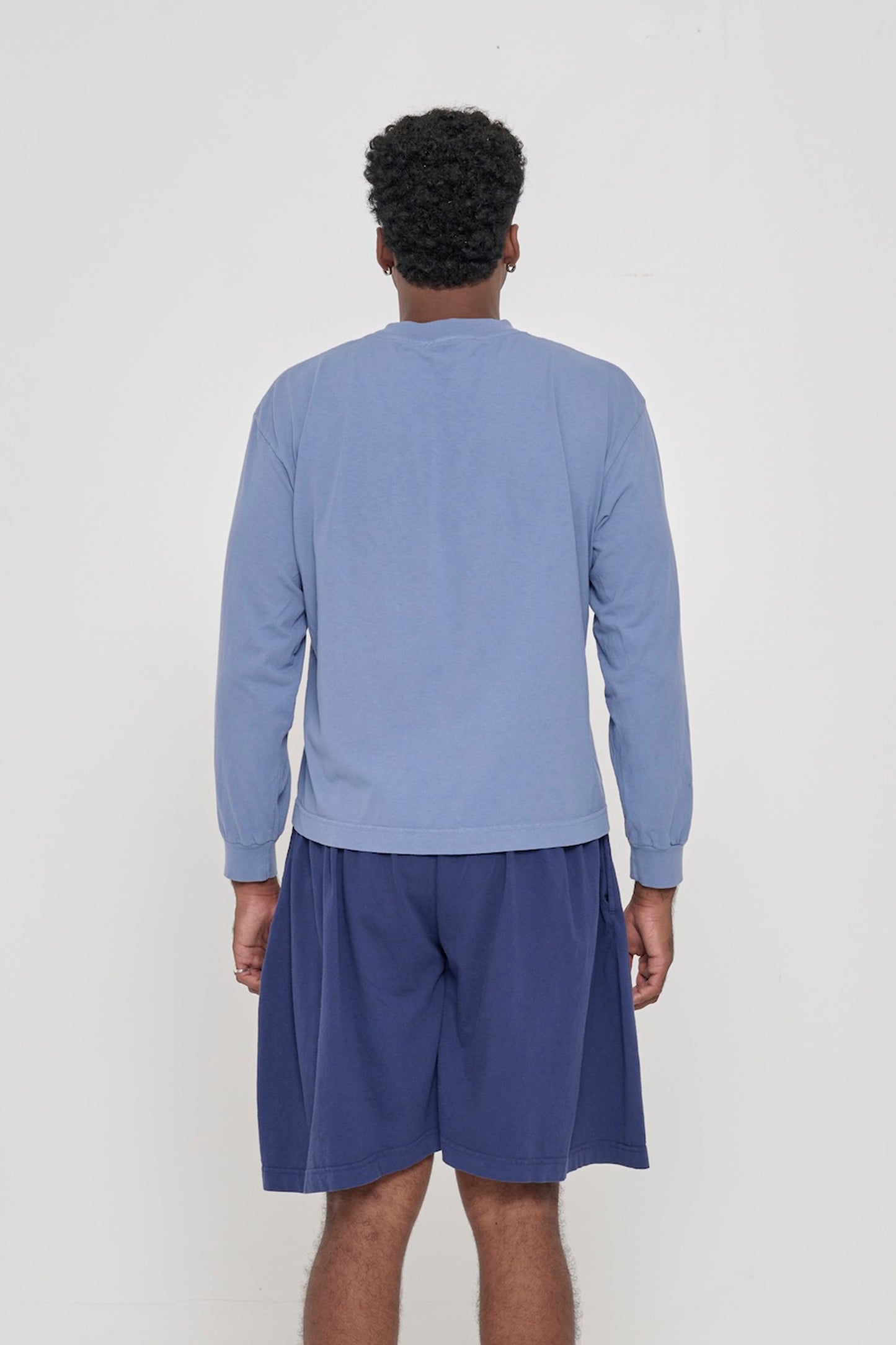 Back view of a person wearing a Periwinkle Long Sleeve Boxier Trash Tee showing fabric drape and relaxed fit throughout.