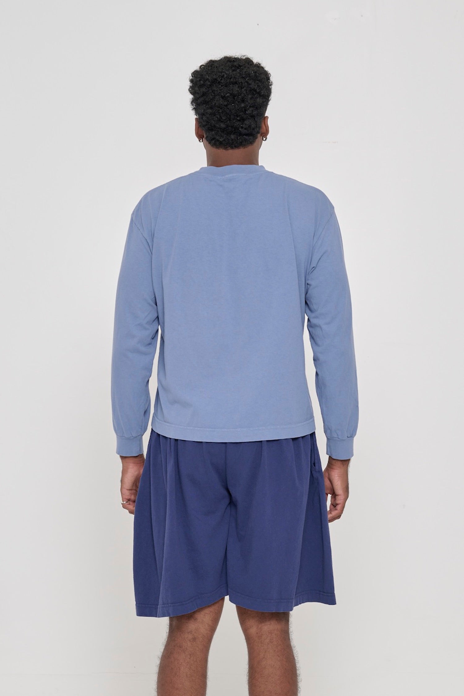 Back view of a person wearing a Periwinkle Long Sleeve Boxier Trash Tee showing fabric drape and relaxed fit throughout.
