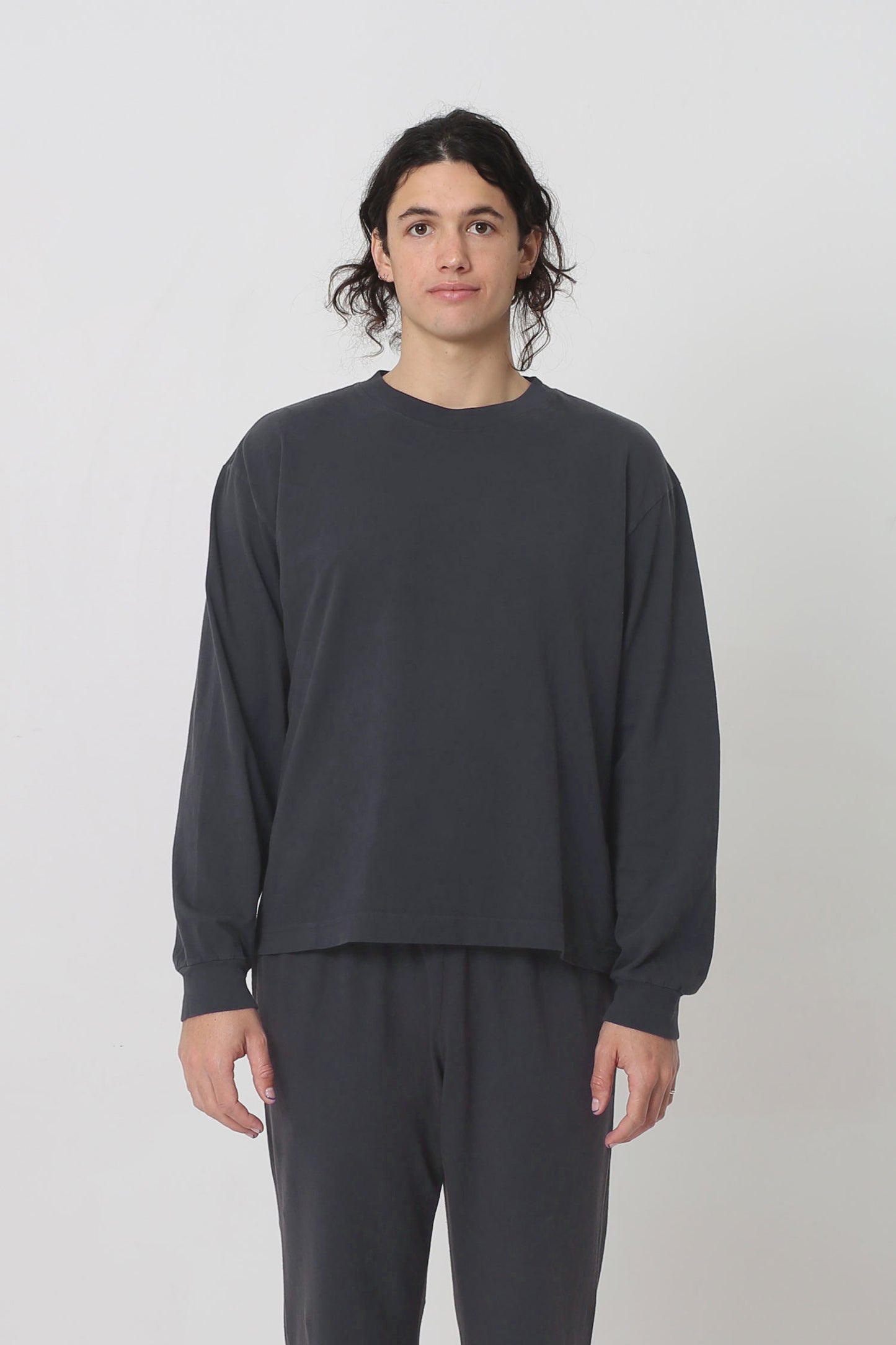 A 6' person in a size M Slate Long Sleeve Boxier Trash Tee. Hem hits their middle hip. 