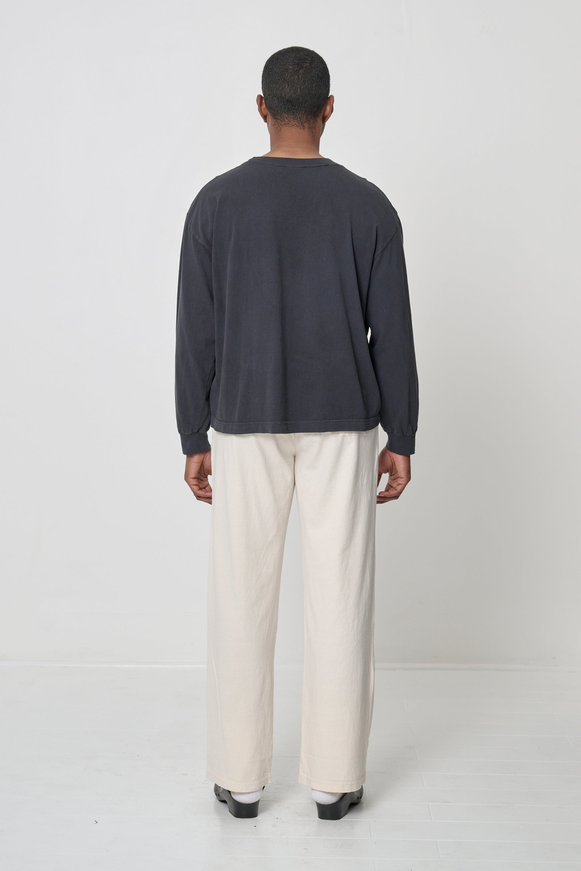 Close up back view of person wearing Black Long Sleeve Boxier Trash Tee showing relaxed drape of the fabric.