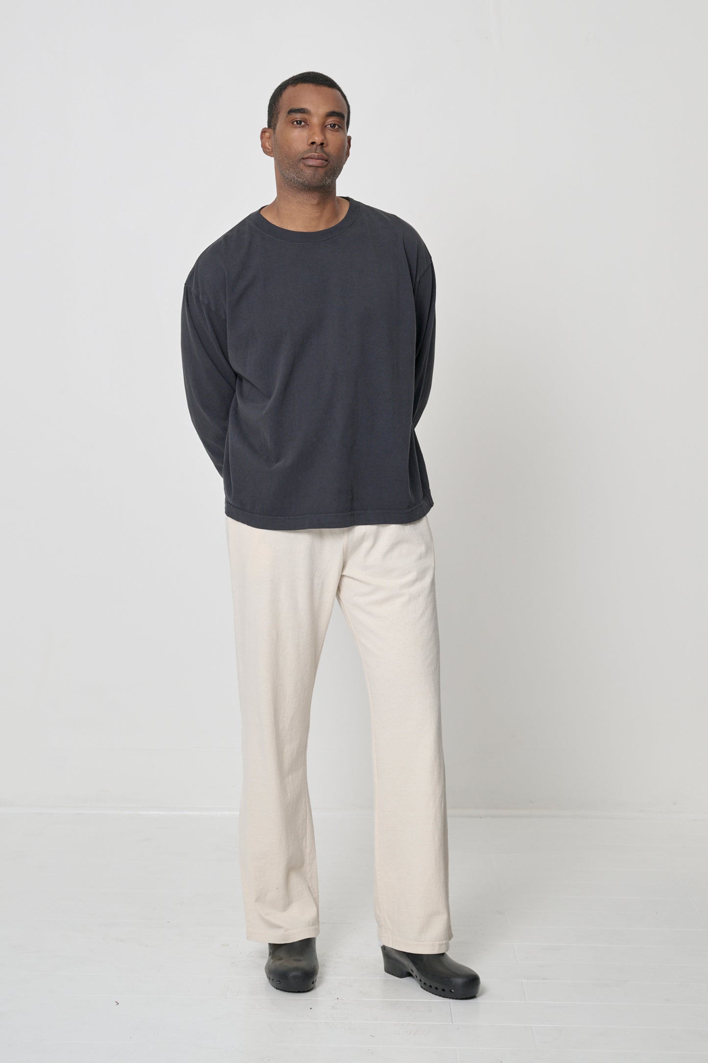 Full length view of person wearing Slate Long Sleeve Boxier Trash Tee with hands behind his back, showing relaxed fix and ease of movement.