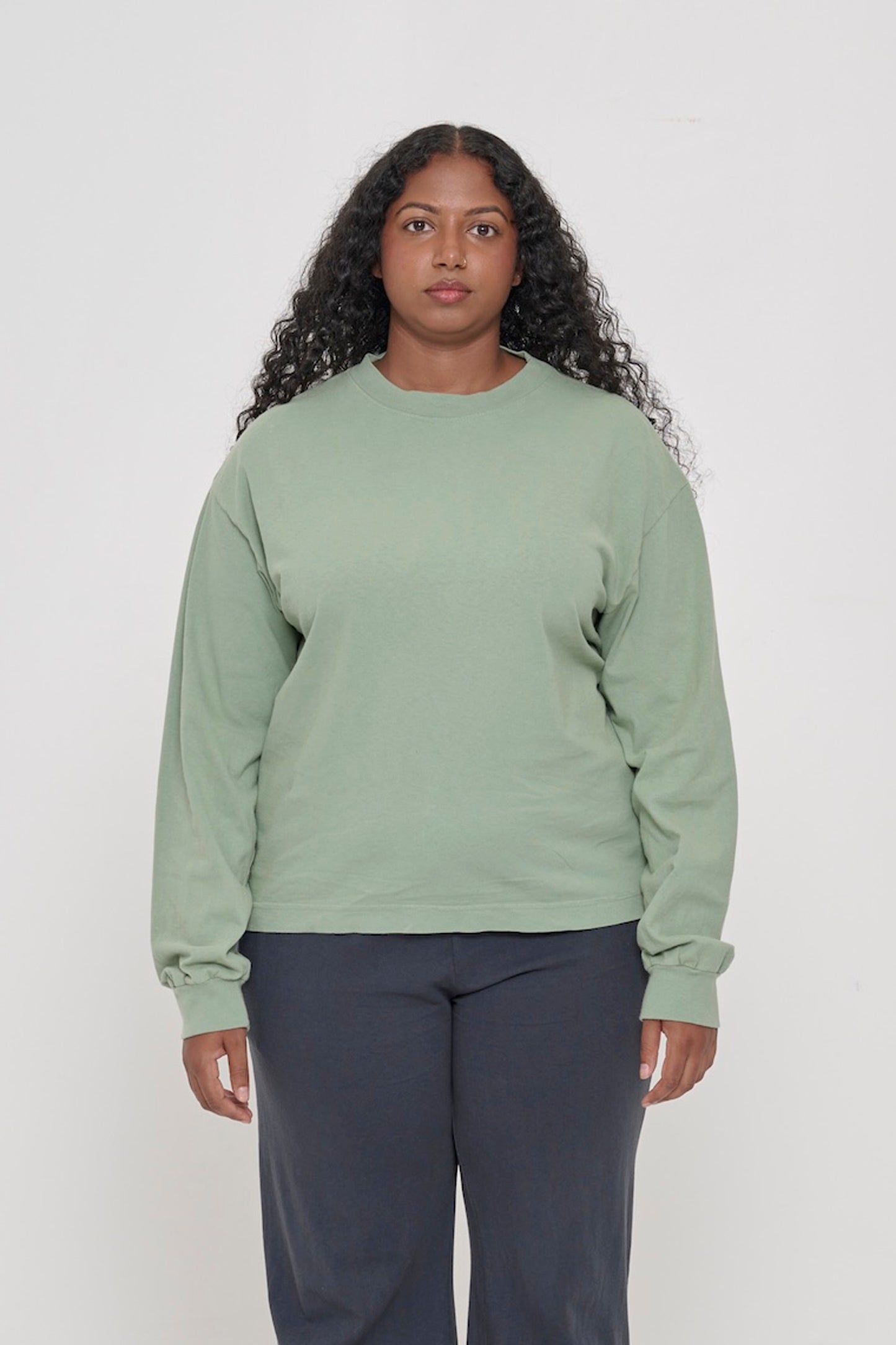 A woman in a Wasabi Long Sleeve Boxier Trash Tee. Shirt hem hits the middle of the hip. 