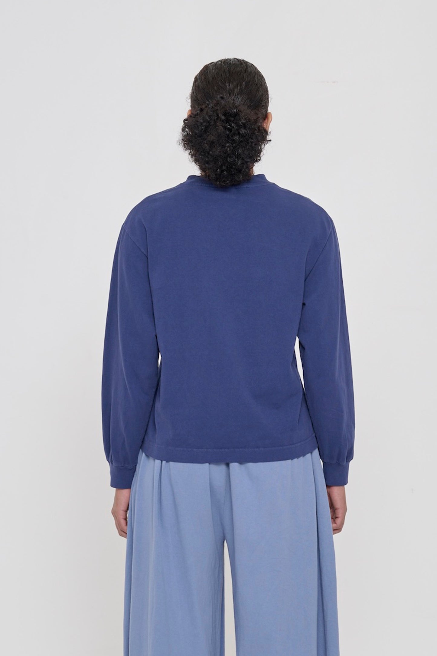 Back view of a person wearing a Washed Navy Long Sleeve Boxier Trash Tee showing fabric drape and relaxed fit throughout.